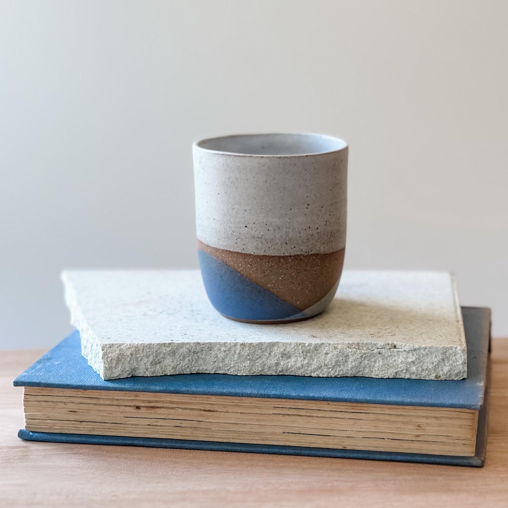 Ceramic cup with two-tone design on top of a book