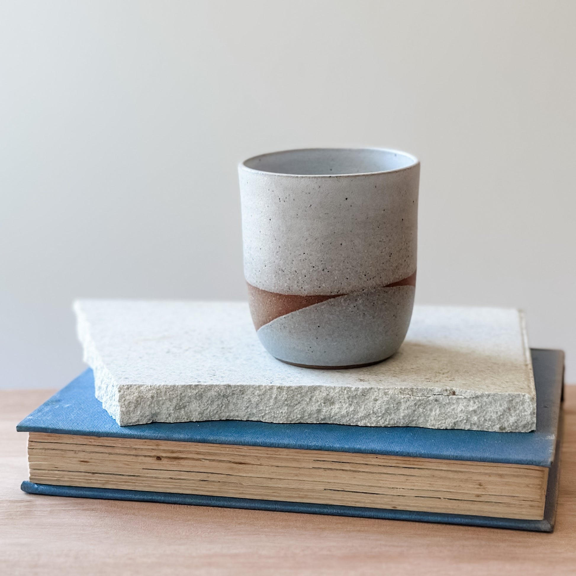 Ceramic cup with a unique design on top of two books