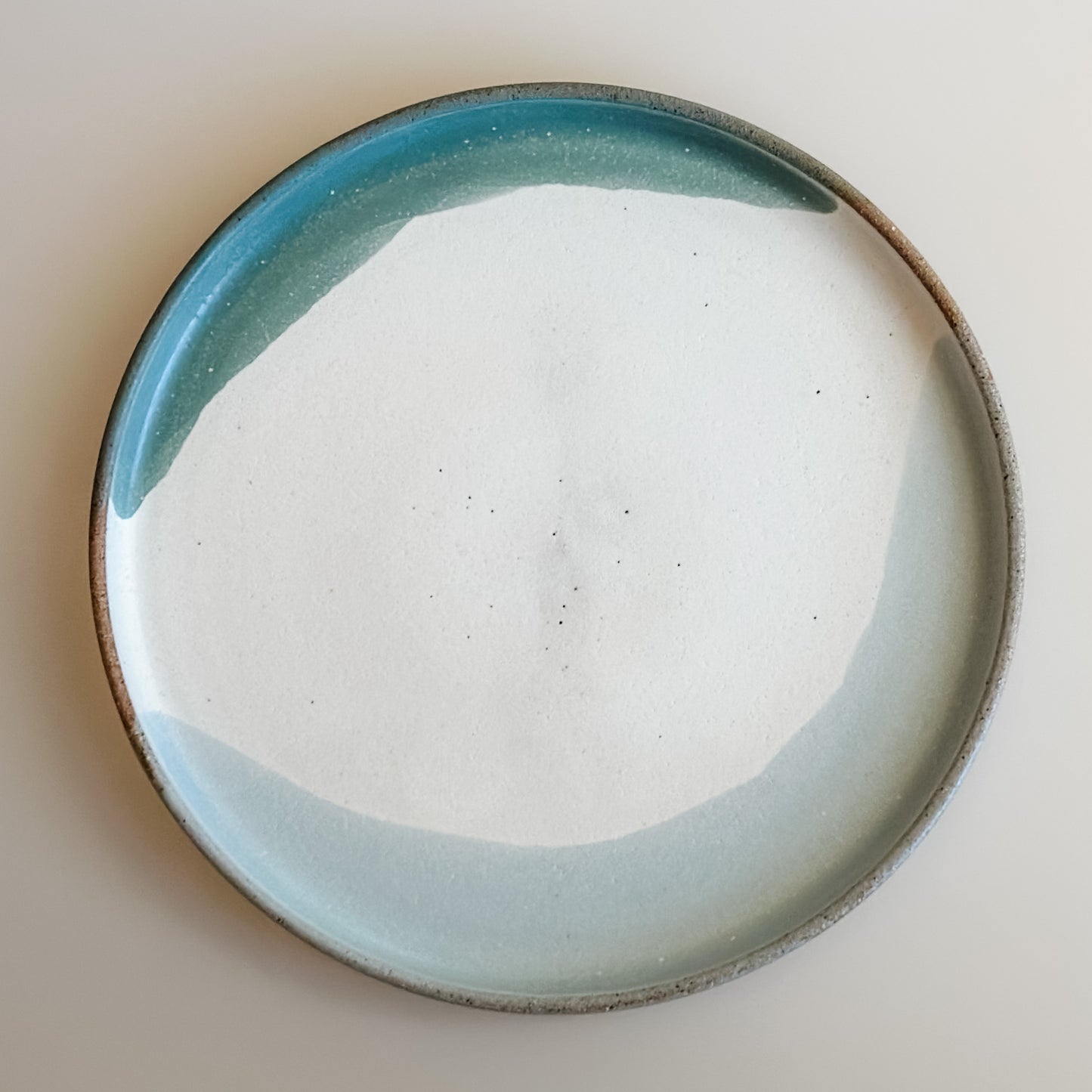 An aerial view of the small Tidal Handmade Ceramic Plate in a white, green and blue-grey glaze. The plate sits on a white background.